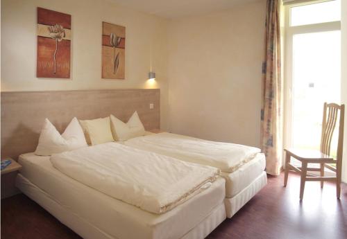 Cette chambre comprend un grand lit blanc et une chaise. dans l'établissement 4 Sterne Apartment Dünensand Sauna und Terasse in Südwestlage, à Lobbe
