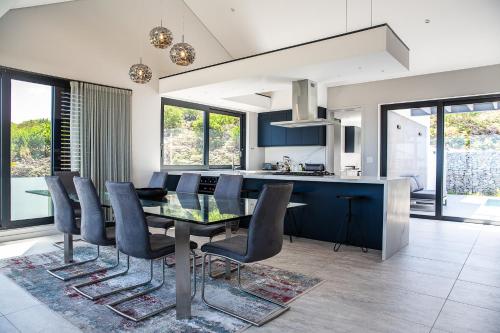 a kitchen and dining room with a glass table and chairs at Miles End Pezula in Knysna