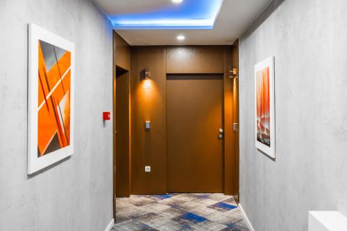 a hallway with a brown door and paintings on the walls at Hotel Biss in Zenica
