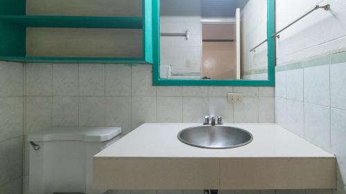 ein Badezimmer mit einem Waschbecken, einem Spiegel und einem WC in der Unterkunft RedDoorz at Broadway Court Apartelle II Quezon City in Manila