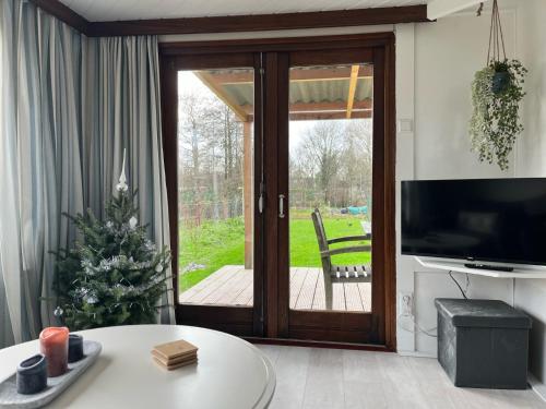 a living room with a sliding glass door at Vrijstaand chalet met veel buitenruimte en veranda in Zuid-Scharwoude