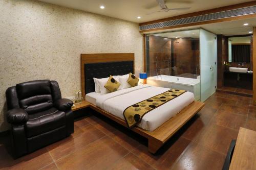 a bedroom with a large bed and a black chair at Grand Kailash Hotel in Aurangabad