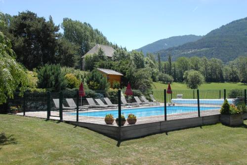 a swimming pool with chairs and plants in a yard at CHALET LES ECUREUILS in Barcelonnette