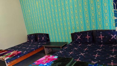una camera con due letti e una parete verde di Hotel Gauri Shankar Palace Murari a Barkot