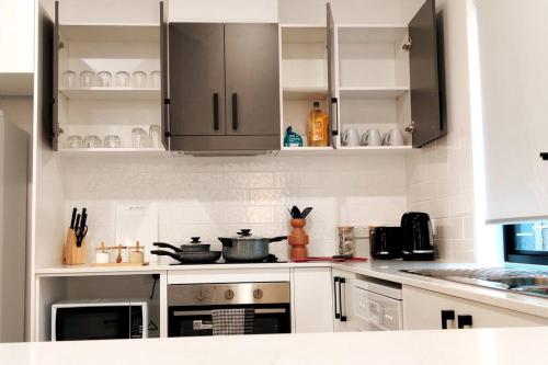 a kitchen with white cabinets and stainless steel appliances at BAYWATER RETREAT- WALK TO WATER - QUIET STREET - CENTRAL TO BRISBANE CITY GOLD COAST AND SUNSHINE COASt! in Cleveland