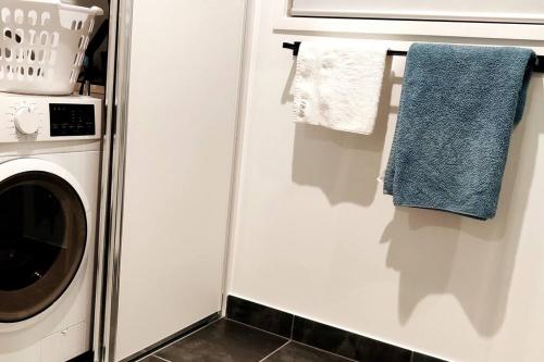 a laundry room with a washing machine and towels at BAYWATER RETREAT- WALK TO WATER - QUIET STREET - CENTRAL TO BRISBANE CITY GOLD COAST AND SUNSHINE COASt! in Cleveland