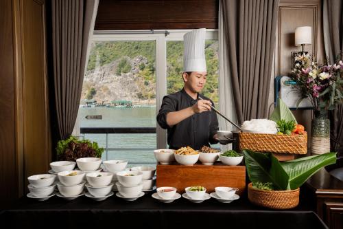a chef standing in a kitchen preparing food at Ambassador Halong Cruise in Ha Long