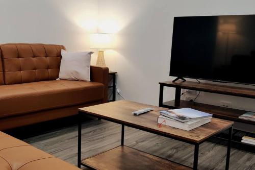 a living room with a couch and a tv at BAYWATER RETREAT- WALK TO WATER - QUIET STREET - CENTRAL TO BRISBANE CITY GOLD COAST AND SUNSHINE COASt! in Cleveland