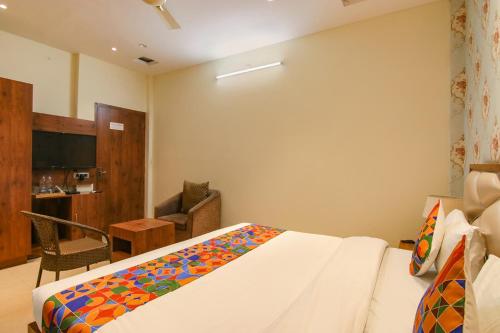 a bedroom with a bed and a chair and a television at FabHotel K9 Regency in Dorāha
