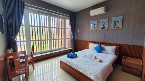 een slaapkamer met een bed en een groot raam bij Khu du lịch Hang Rái - Ninh Thuận in Thôn Thái An