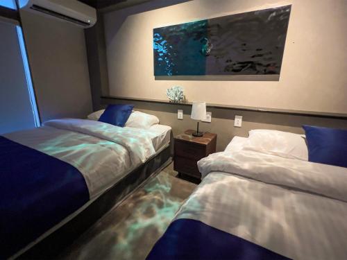 a bedroom with two beds and a painting on the wall at UMI-IRO〜うみいろ下関〜 in Shimonoseki