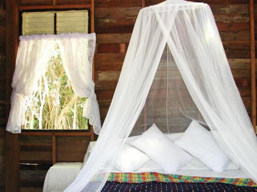 a bed with a mosquito net in a room with a window at Room in Bungalow - Breathtaking Cottage of Koh Pu in Ko Jum