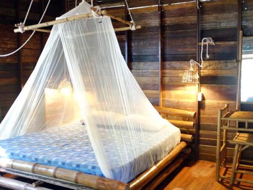 a bed with a net canopy in a room at Room in Bungalow - Breathtaking Cottage of Koh Pu in Ko Jum