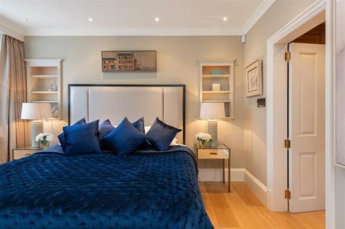 a bedroom with a blue bed with blue pillows at Elegantly Designed Belgravia Townhouse in London