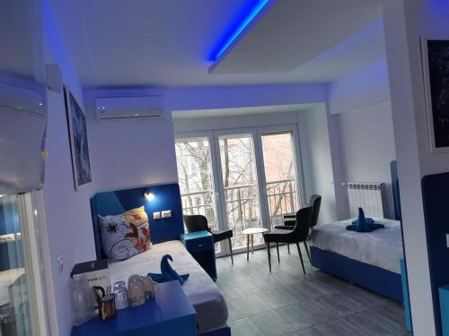 een blauwe kamer met 2 bedden en een raam bij Бутик хотел ресторант брасери Сажитариус in Kyustendil