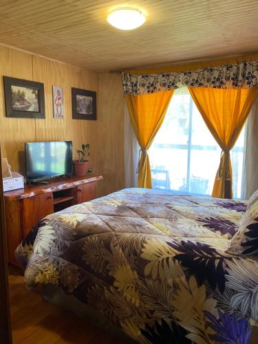 a bedroom with a bed and a flat screen tv at Cabaña Maite in Panguipulli