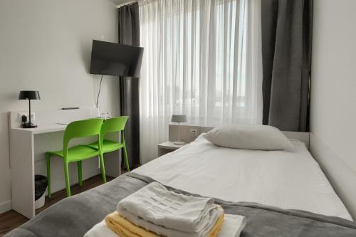 a bedroom with a bed and a desk and a green chair at Płonia Resort in Szczecin