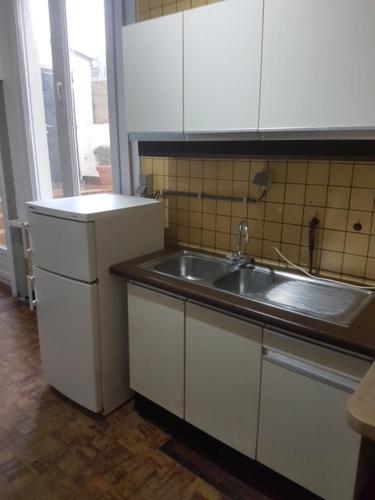 uma cozinha com armários brancos e um lavatório em APPARTEMENT GELIJKVLOERS OOSTENDE em Ostend