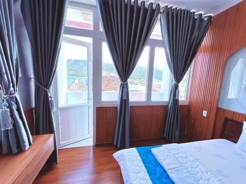 a bedroom with a bed and two large windows at Khu du lịch Hang Rái - Ninh Thuận in Thôn Thái An