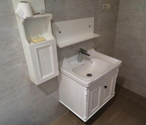 a white bathroom with a sink and a toilet at Chez Fatou et Saladin in Diana