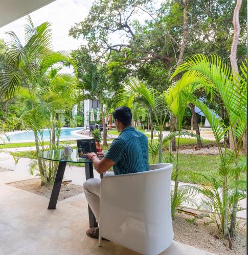 a man sitting at a table with a laptop at Luz de Luna Tulum Suite III in Tulum