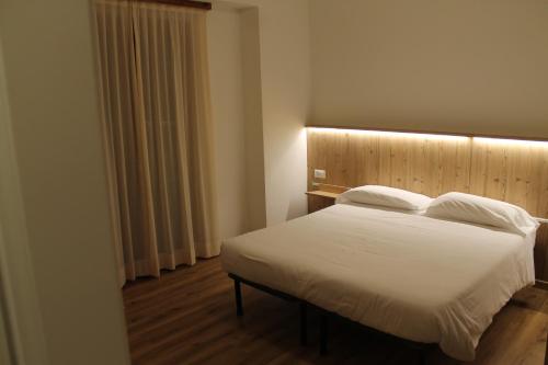 a bedroom with a white bed with a wooden headboard at Hotel Miramonti in Chiesa in Valmalenco