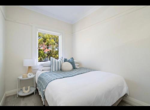 a white bedroom with a bed and a window at Little Manly 3 bedroom Oasis in Sydney