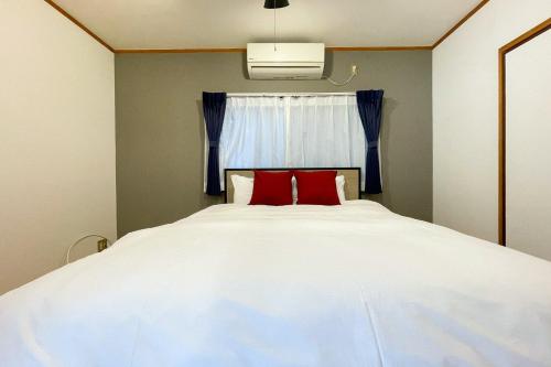 a bedroom with a white bed with two red pillows at Lavie Heights in Osaka