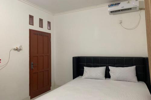 查亞普拉的住宿－OYO 93485 Hotel Kenzie Sentani，卧室配有带白色床单的床和门。