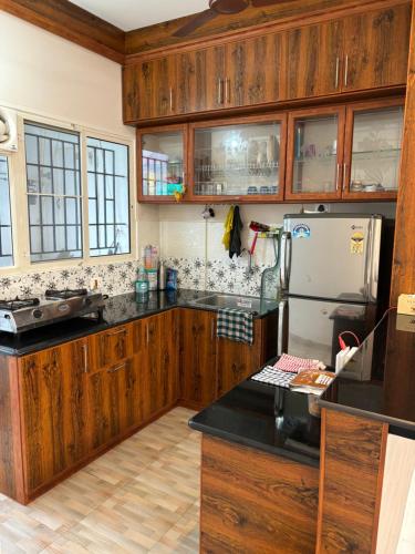 - une cuisine avec des placards en bois et un réfrigérateur dans l'établissement Laus Deo 2 Quiet and Cosy 2BHK apartment on 9th floor, à Trivandrum