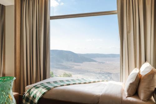 a bedroom with a large window with a mountain view at Ngorongoro Lodge member of Melia Collection - The Leading Hotels of the World in Ngorongoro