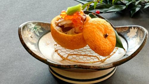 two oranges on a plate on a table at Tabist Nikkokinugawa Onsen Kiyomizu no Yado in Nikko