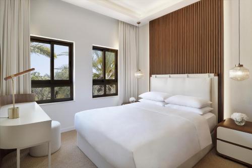 a white bedroom with a white bed and windows at Elara Villas in Dubai