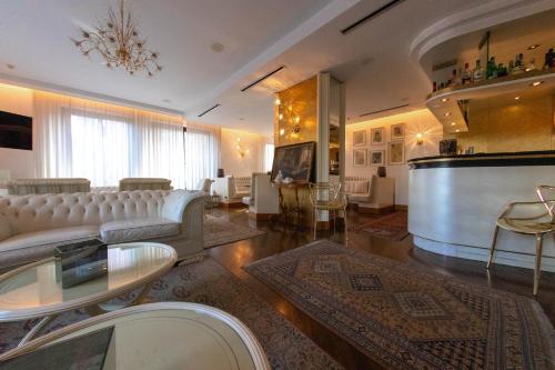 a large living room with white furniture and a bar at Parc Hotel Flora S in Riva del Garda