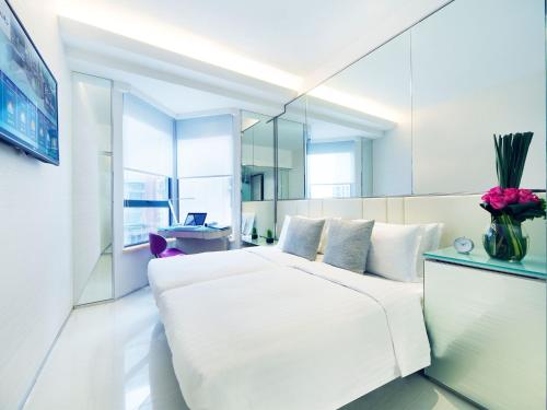 a bedroom with a large white bed and a mirror at iclub Fortress Hill Hotel in Hong Kong