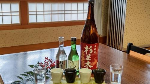 two bottles of wine sitting on a table with glasses at Tabist Nikkokinugawa Onsen Kiyomizu no Yado in Nikko
