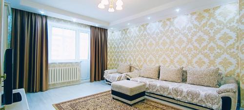 ein Wohnzimmer mit einem Sofa und einem Fenster in der Unterkunft Comfortable apartment on Sarayshyq street 7-1 in Astana