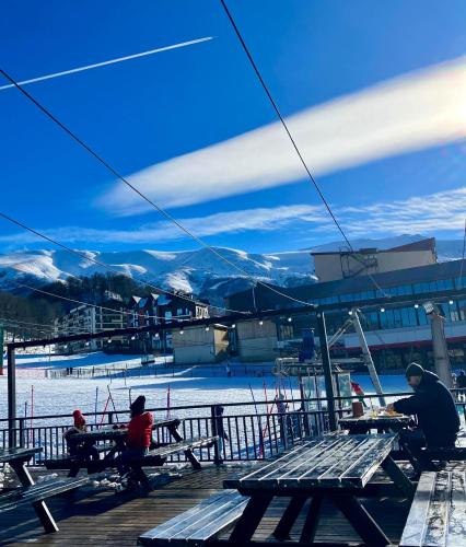 a group of people sitting at picnic tables on a ski slope at Vista Studio in Bakuriani
