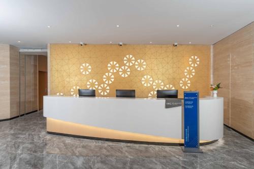 a reception desk in a lobby with a gold wall at Holiday Inn Express Weifang City Center by IHG in Weifang