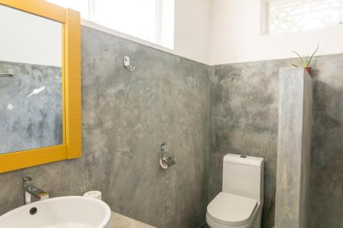 a bathroom with a white toilet and a sink at Lotus Surf And Wellness in Ahangama