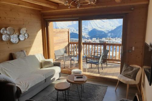 a living room with a couch and a balcony at LOdyssée 203 in La Toussuire