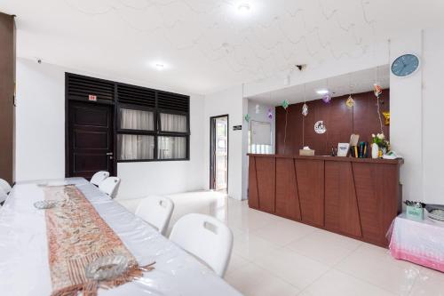 a kitchen with a long table and white chairs at RedDoorz Syariah near Banda Aceh Convention Hall in Lamnyong