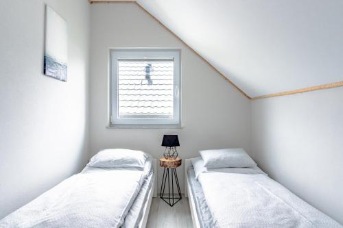 two beds in a room with a window at Domki Leśne Zacisze - Domki z basenem in Jastrzębia Góra