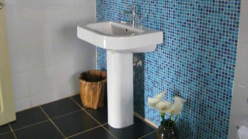 La salle de bains est pourvue d'un lavabo blanc et de carrelage bleu. dans l'établissement Nyungwe Hill View Hotel, à Rwumba