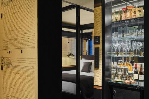 a room with a bed and a display case with bottles at Duxton Reserve Singapore, Autograph Collection in Singapore