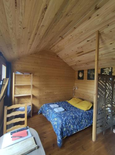 a bedroom with a bed in a wooden cabin at Chalet de fred in Saint-Ouen-de-Mimbré