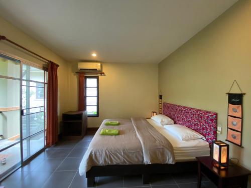 a bedroom with a large bed and a window at Sweet Mango Khaolak in Khao Lak