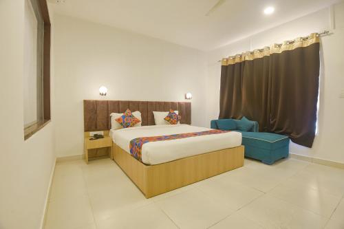 a bedroom with a large bed and a blue chair at FabHotel Morjim Bliss in Morjim