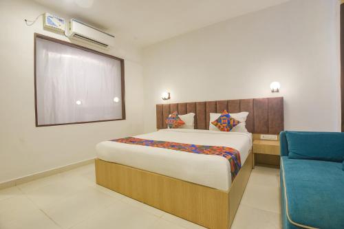 a bedroom with a large bed and a blue chair at FabHotel Morjim Bliss in Morjim