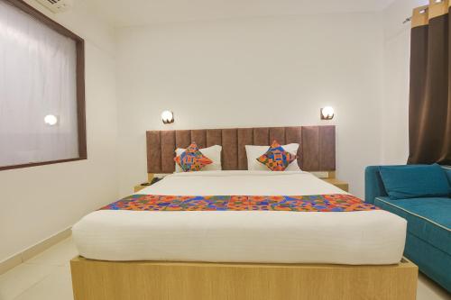 a bedroom with a large bed and a blue couch at FabHotel Morjim Bliss in Morjim